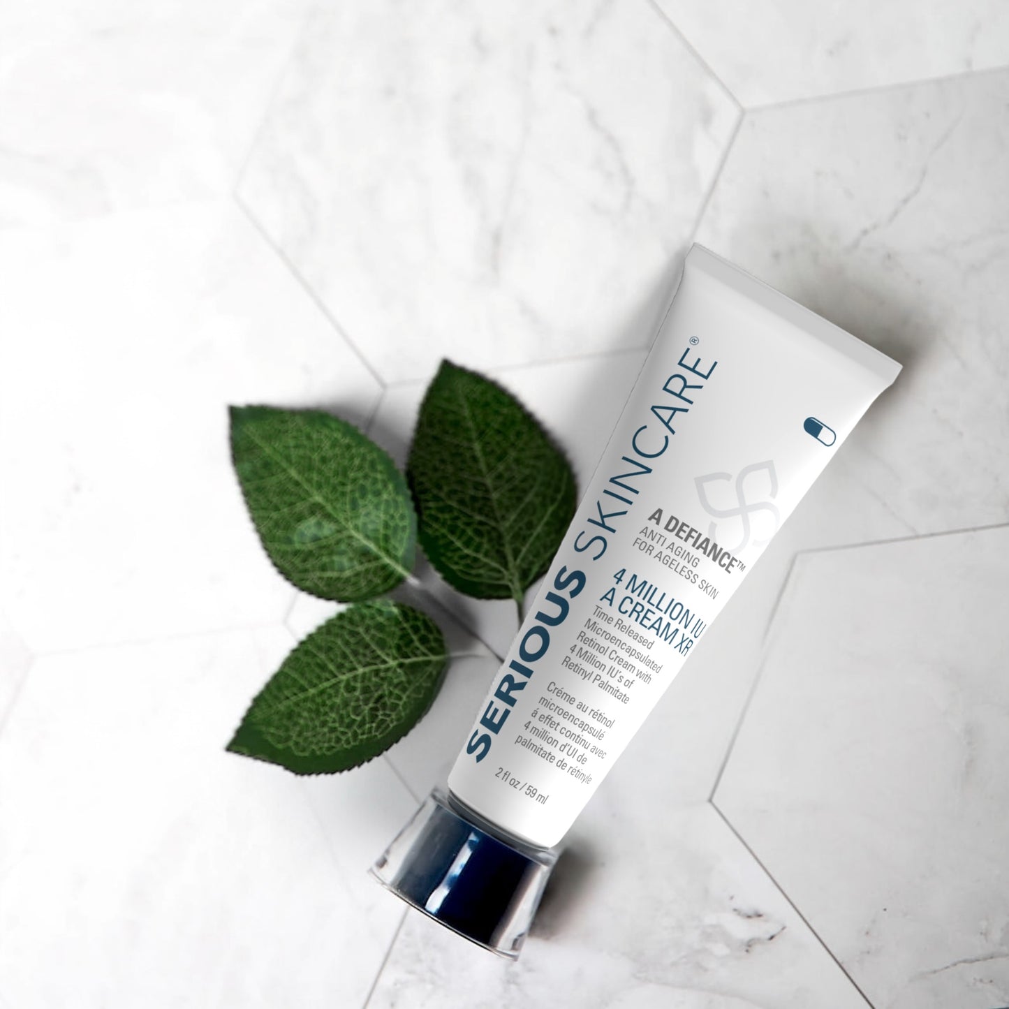 Skincare cream tube with green leaves on a light marble background