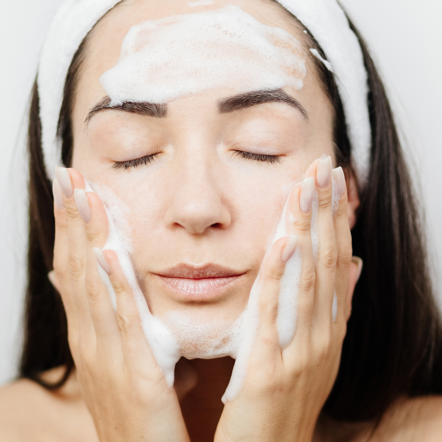 Female applying a gentle facial cleanser to her skin 