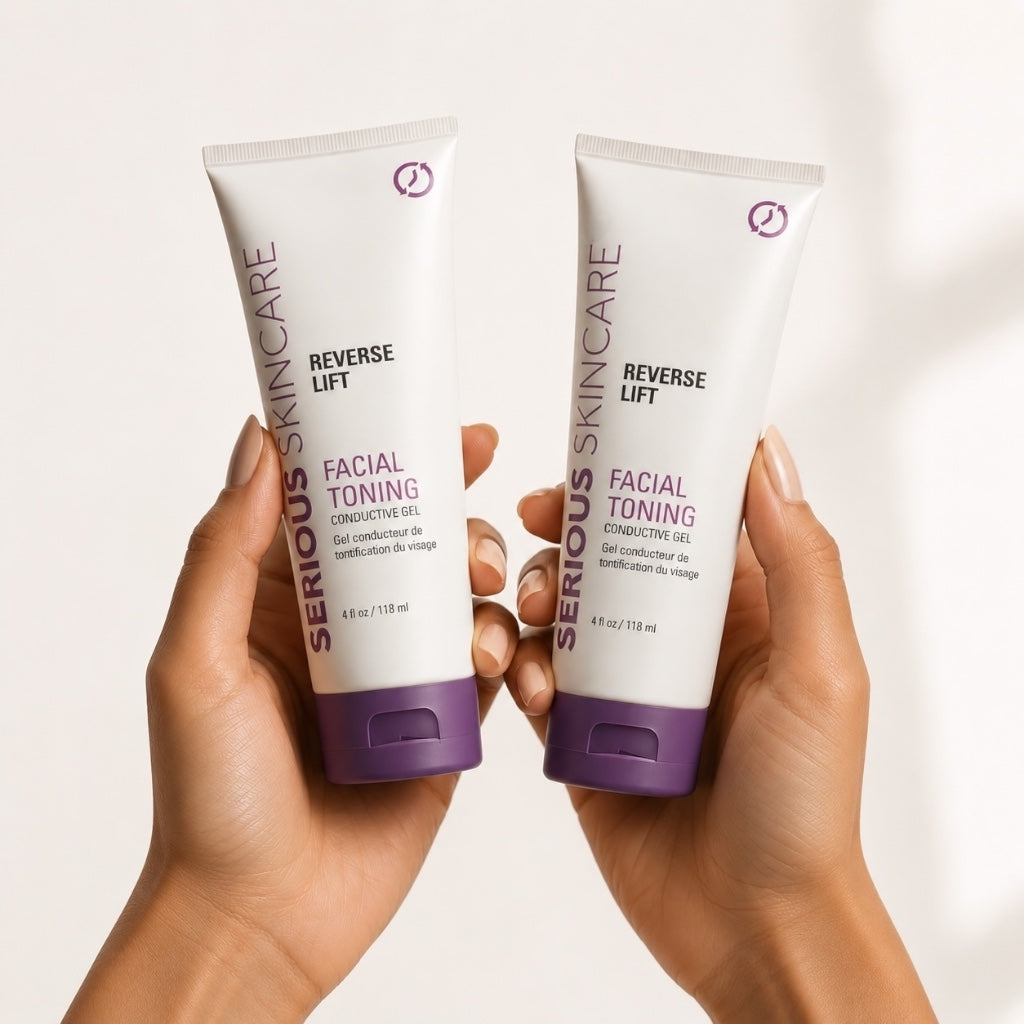 Two hands holding two white tubes of Serious Skincare Reverse Lift Facial Toning Conductive Gel against a clean white background.