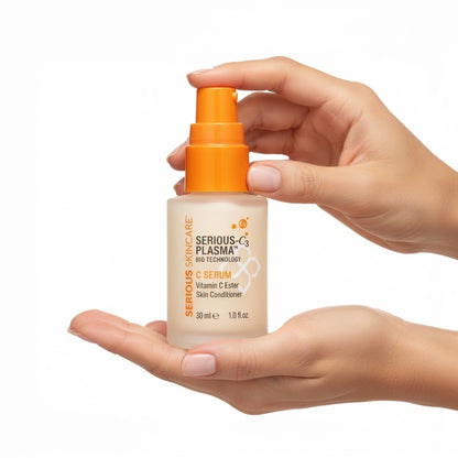 Hand holding a bottle of 'Serious Plasma' C Serum with an orange pump on a white background