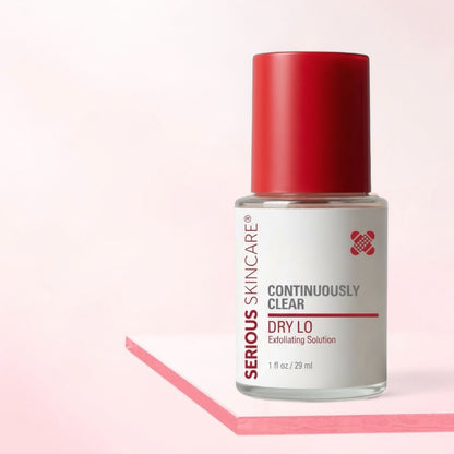 Serious Skincare bottle with red cap on a light pink background.  Serious Skincare Continuously Clear Dry Lo Exfoliating Solution in a 1 fl oz clear bottle with a red cap and white label, on a white background. Serious Skincare Dry Lo Spot Treatment for blemishes and problem-prone skin