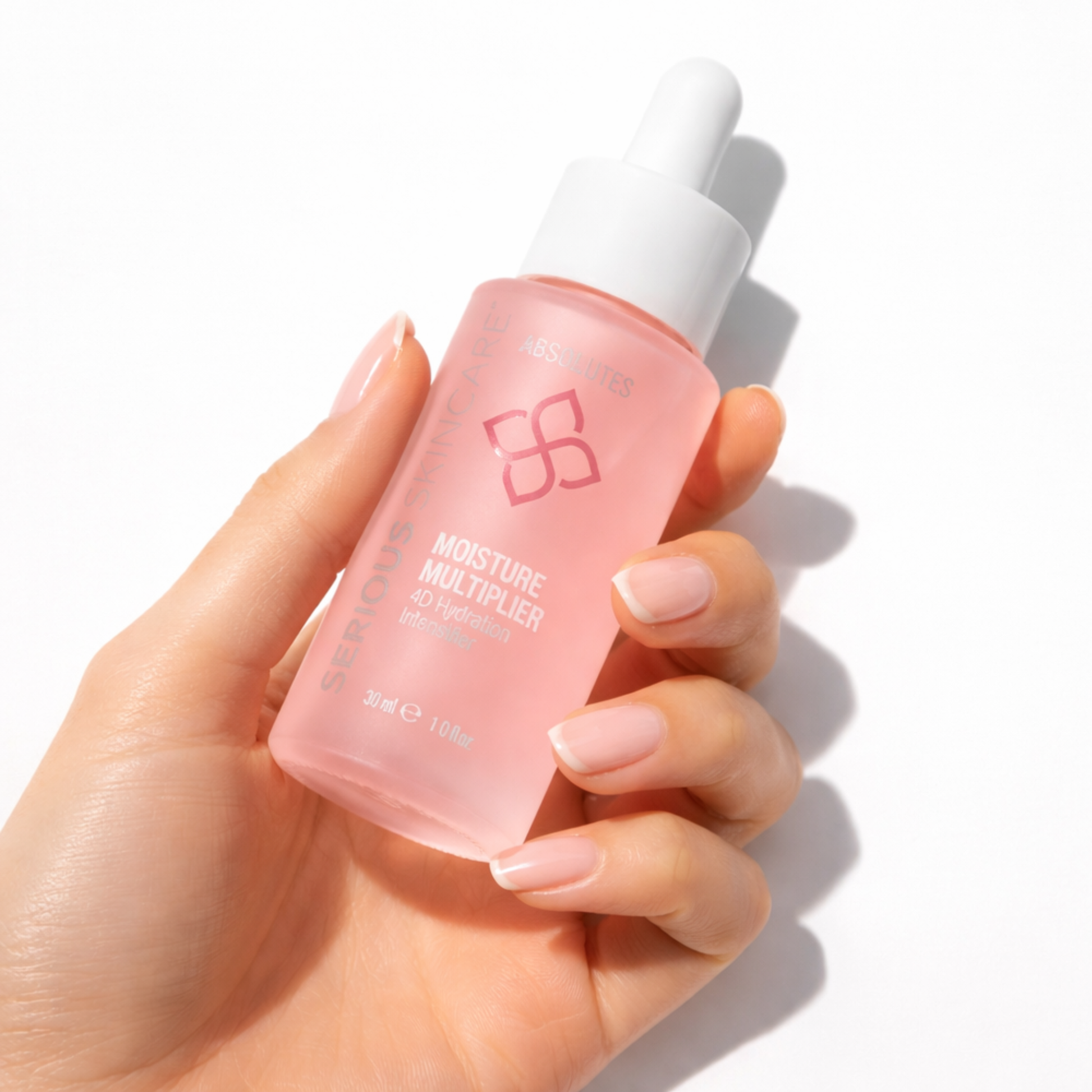 Hand holding a pink skincare bottle labeled 'Moisture Multiplier' on a white background