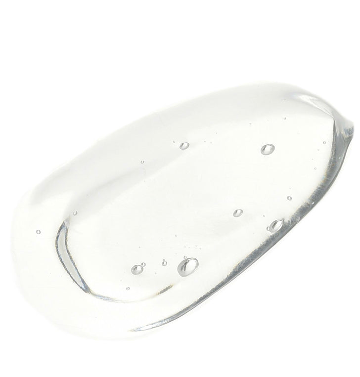 A glossy, translucent droplet of clear gel or liquid cosmetic product on a solid white background.